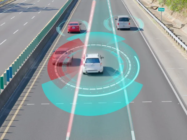 Car driving down freeway with graphic representation of ADAS scanning around the car.
