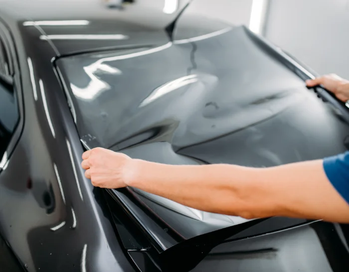 Worker applying tint to auto windshield.