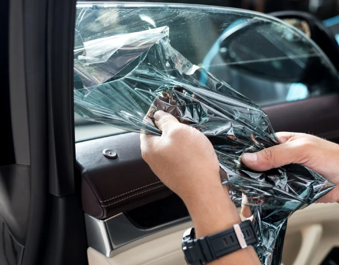 Technician peeling off old tinting from car window.