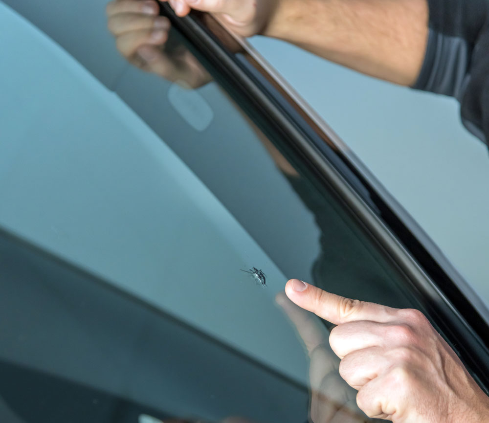 Closeup of glass tech pointing at rock chip on windshield.